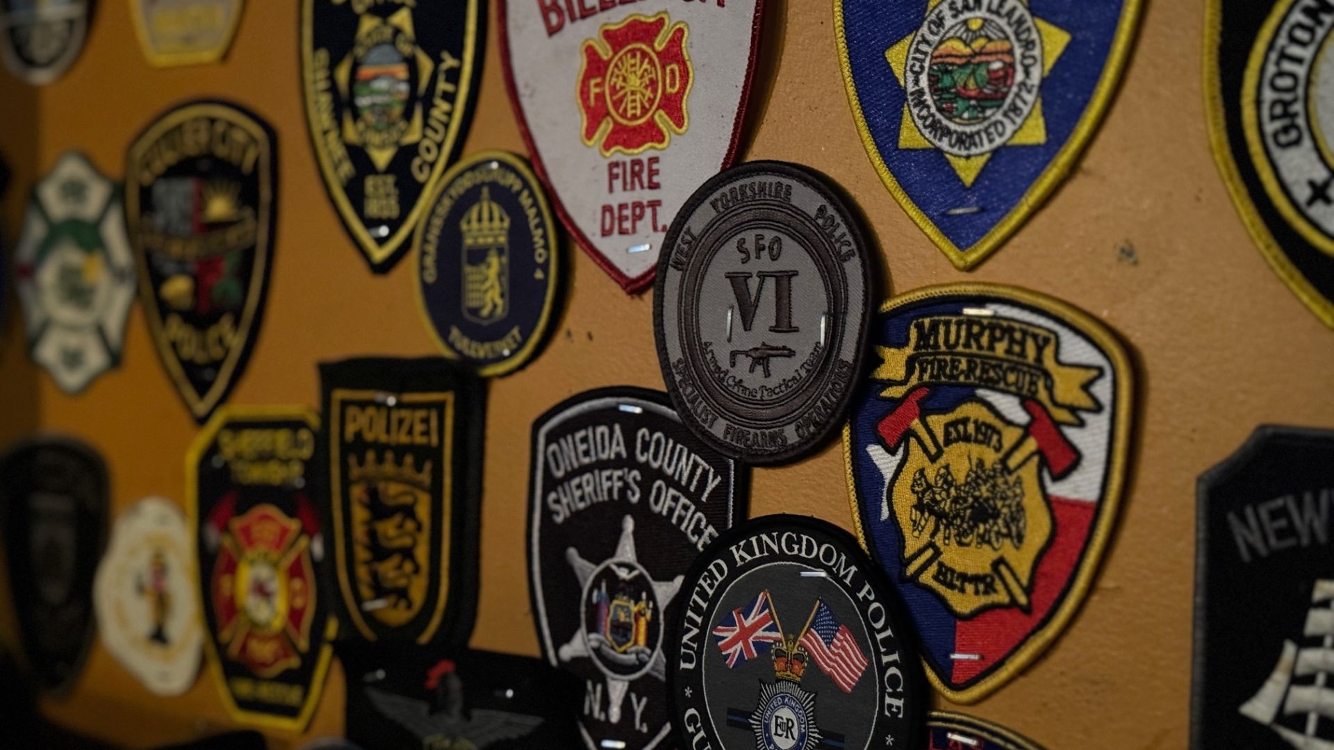 many different fire department and police badges stapled to a wall