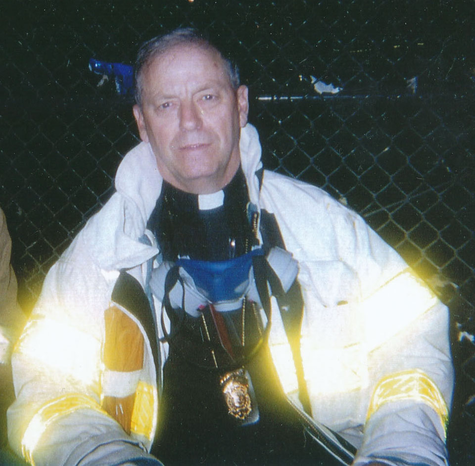 Father Don Milligan poses for a photo at Ground Zero during the recovery operations. He has a filtered face mask around his neck.
