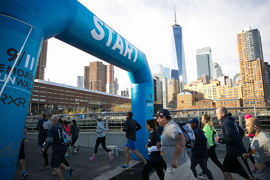 Participants of the 2015 9/11 Memorial 5K Run and Walk pass the starting line. One World Trade Center and other buildings of lower Manhattan are visible in the background.