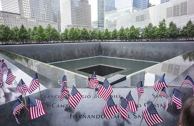 Small American flags have been placed at names on the bronze parapets of the south pool at the 9/11 Memorial.