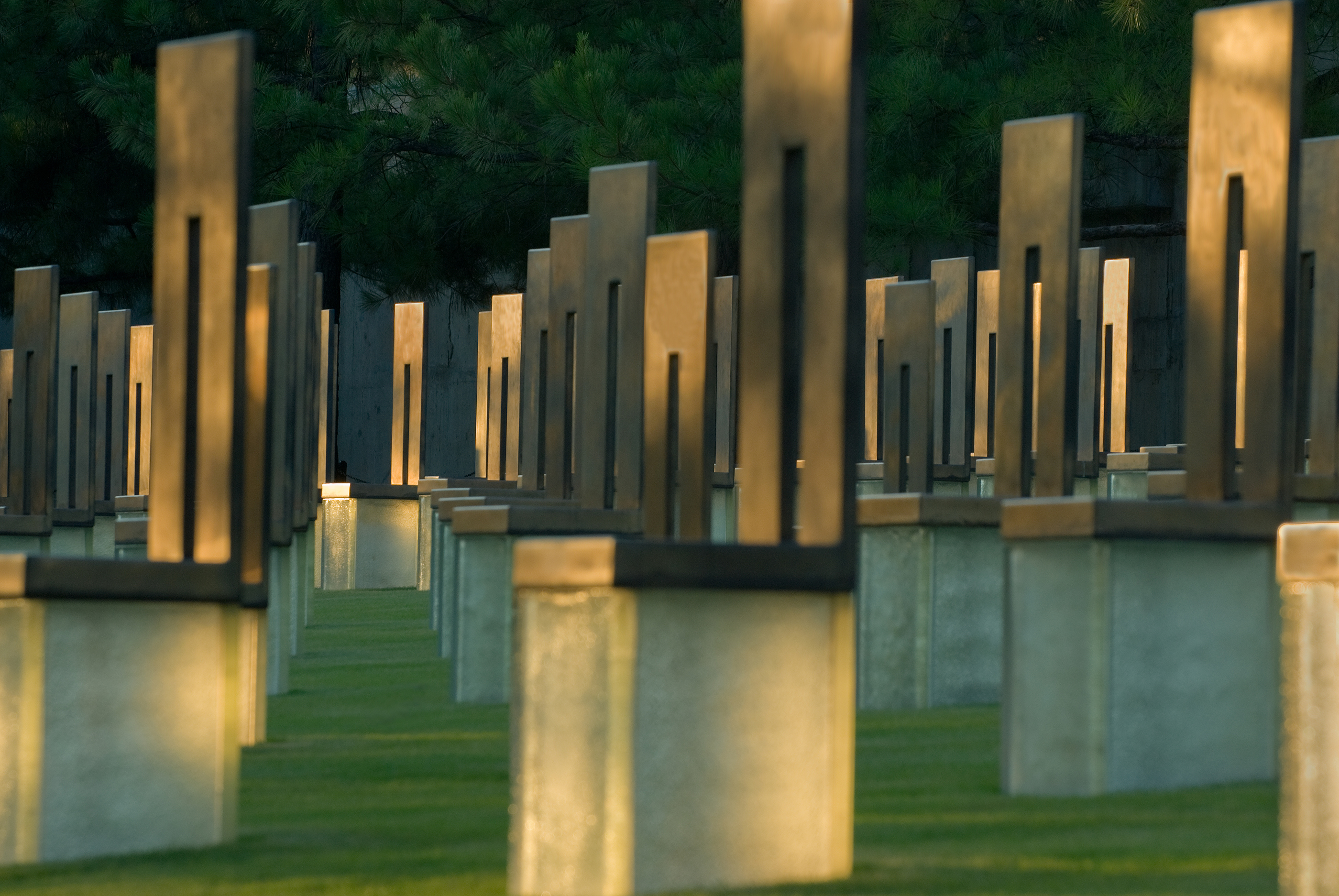 Sculptures of empty chairs fill a grassy field at the site of the Oklahoma City National Memorial and Museum. Sunlight passes through the chairs.