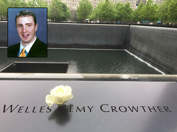 A white rose has been placed at the name of Welles Crowther on the 9/11 Memorial in honor of his birthday. An inset shows a professional photo of Crowther, who is smiling in a suit and tie.