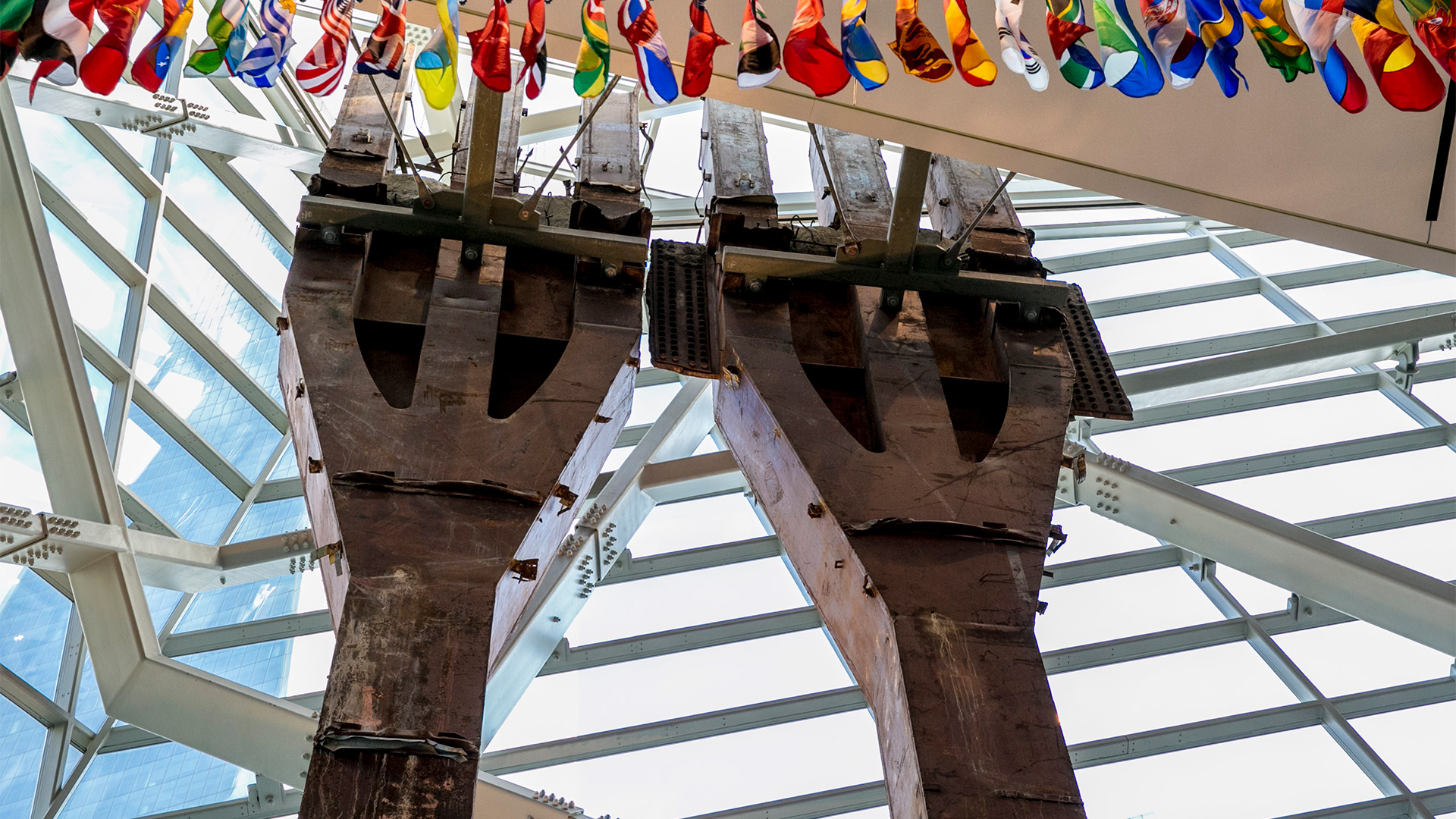 Steel tridents against glass Museum wall bordered by flags from around the world