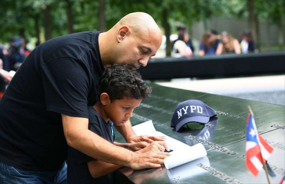 A man and a young boy make an etching of a loved one’s name inscribed on the Memorial.