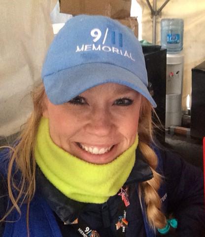9/11 Memorial visitor services volunteer Kelly Morrissey smiles for a photo while wearing a light blue Memorial hat.