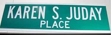 A green and white street sign reads Karen S. Juday Place.