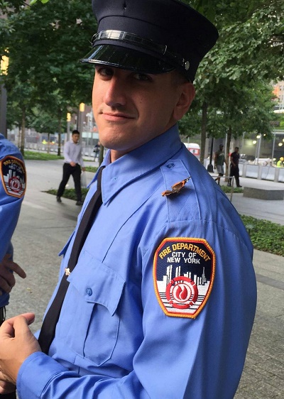 A probationary EMT wears a formal FDNY outfit as he smiles as a butterfly lands on his shoulder at the 9/11 Memorial.