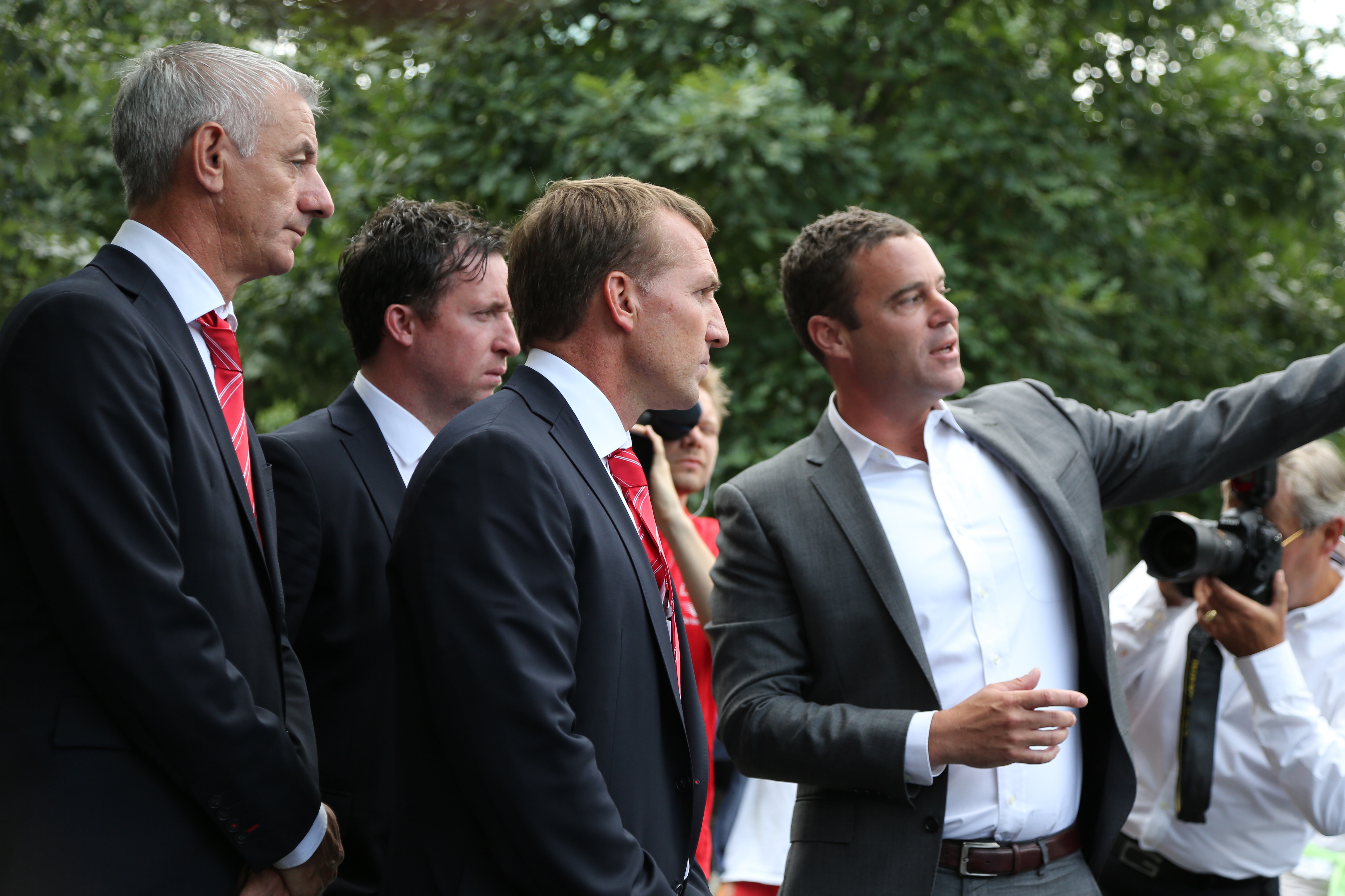 Liverpool soccer players Ian Rush, Robbie Fowler and Brendan Rodgers stand next to 9/11 Memorial President Joe Daniels as Daniels points to something out of view on Memorial plaza.