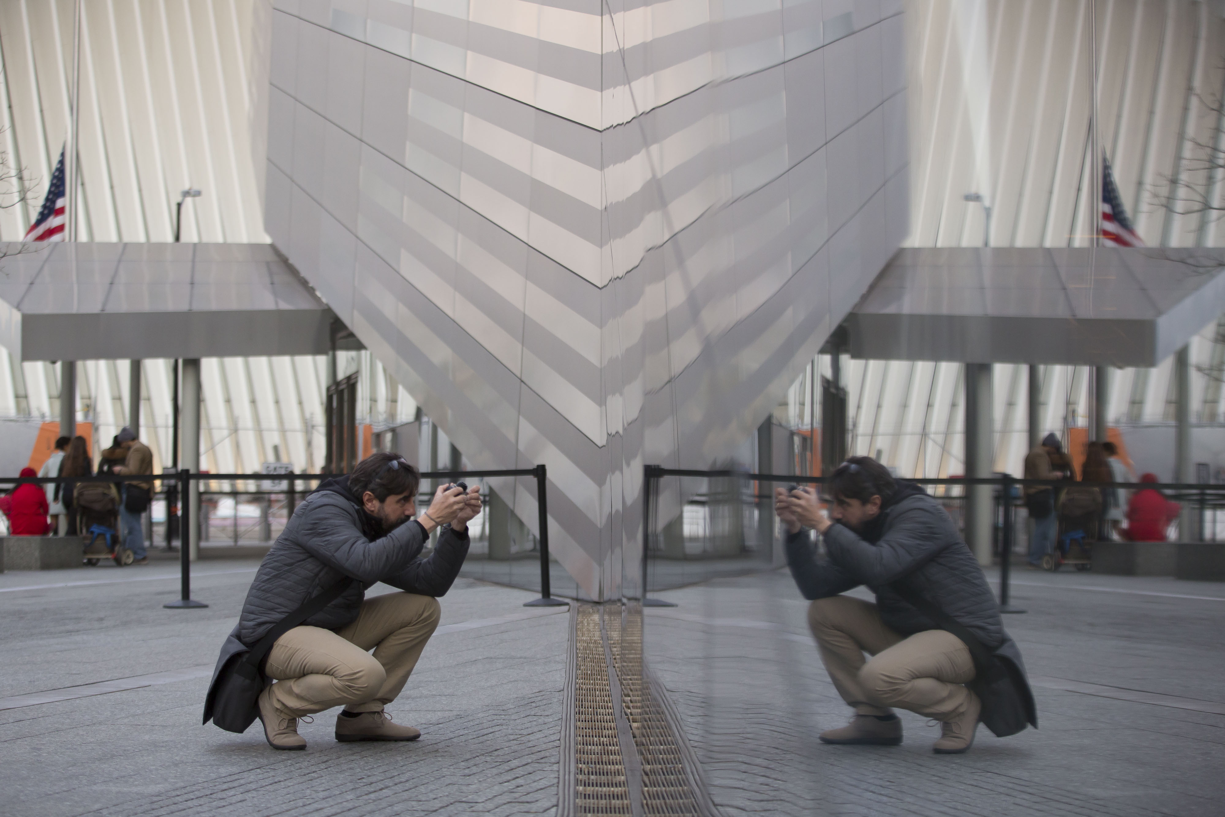 A visitor to the 9/11 Memorial Museum photographs his reflection in the glass of the Museum Pavilion.