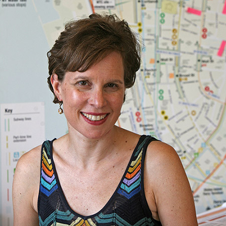 Elizabeth Berger, the president of the Alliance for Downtown New York, smiles for a photo in front of a map of New York City.
