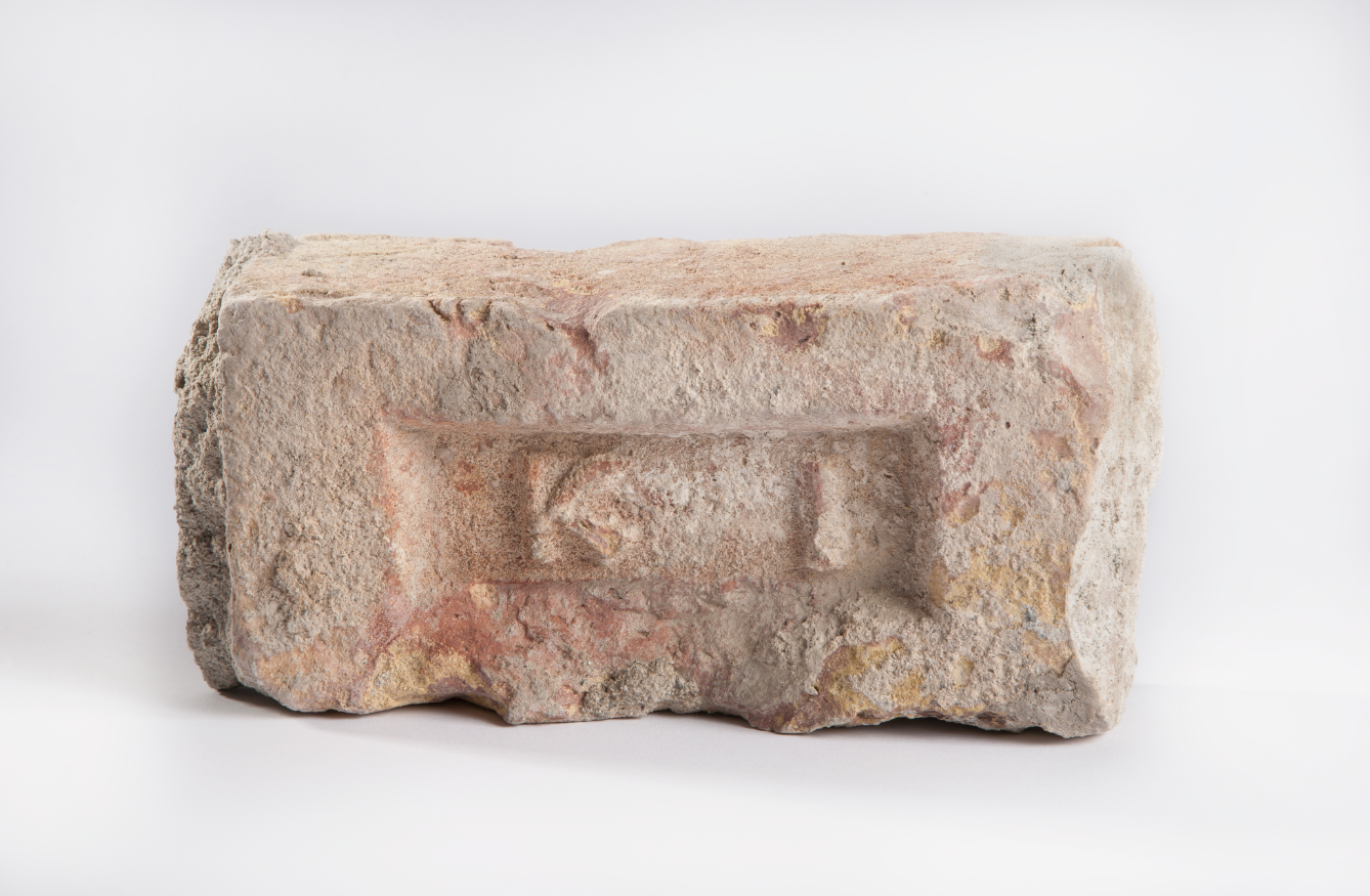 A tan and red–colored brick from Osama bin Laden’s fortified compound is displayed on a white surface at the Museum.