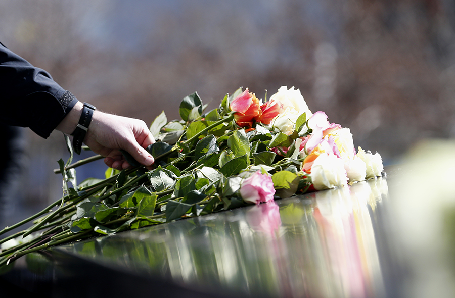 A person places a bundle of multicolored roses at a name on a bronze parapet at the Memorial during a ceremony remembering the victims of the 1993 World Trade Center bombing.