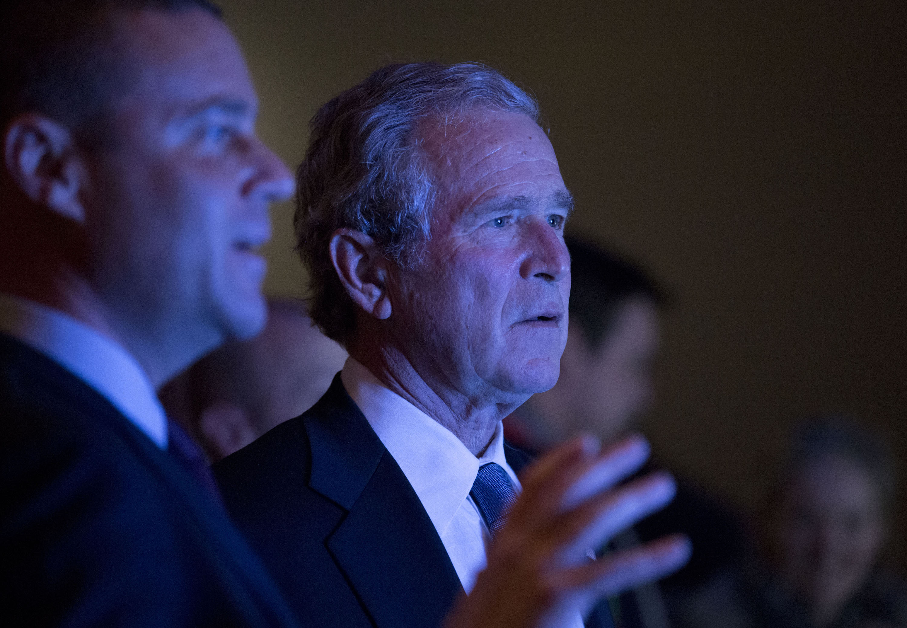 Former President George W. Bush looks at an object out of view as he visits the 9/11 Memorial Museum.