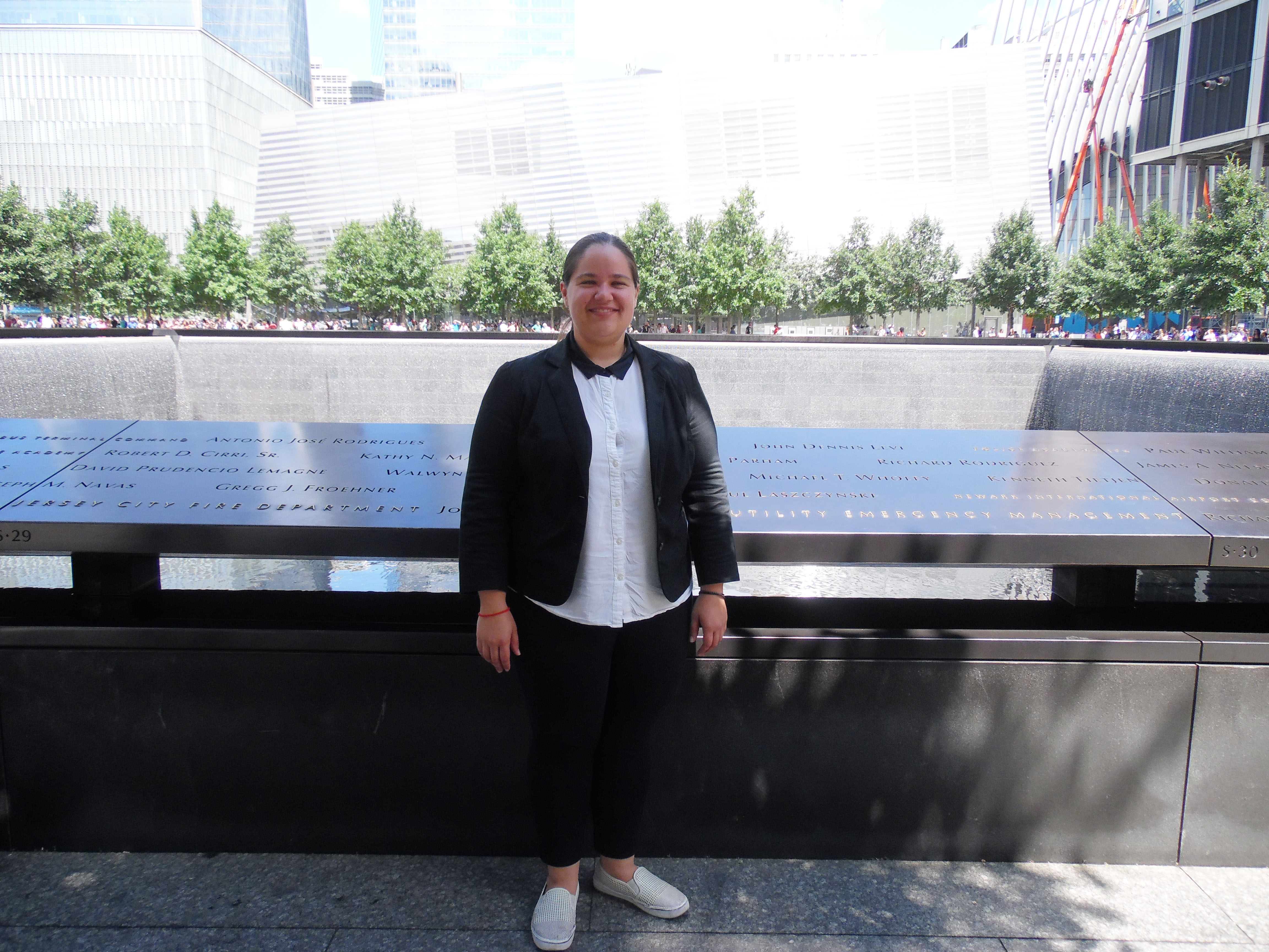 Exhibitions intern Chelsea Levine stands beside the south reflecting pool on the 9/11 Memorial plaza.