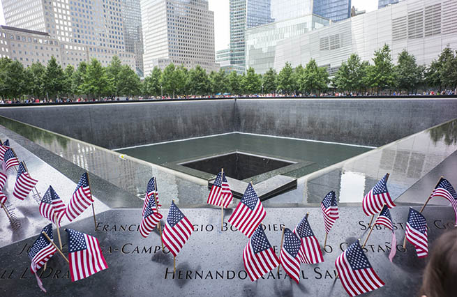 Small American flags have been placed at names on the bronze parapets of the south pool at the 9/11 Memorial.