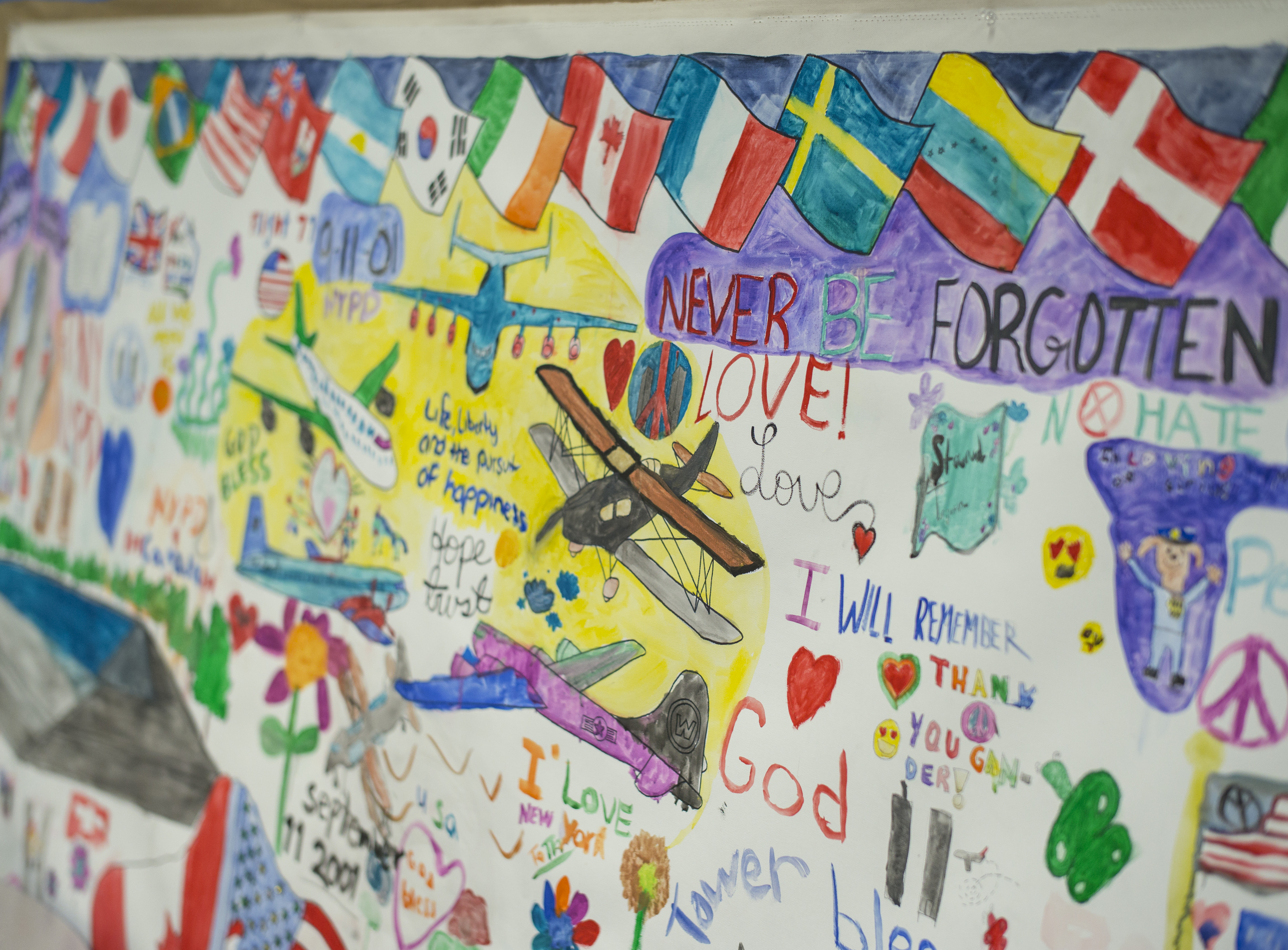 A mural created for Gander, Newfoundland, thanks the town for hosting stranded travelers on 9/11. The colorful mural includes drawings of planes, hearts, flowers, peace signs, and messages of thanks.