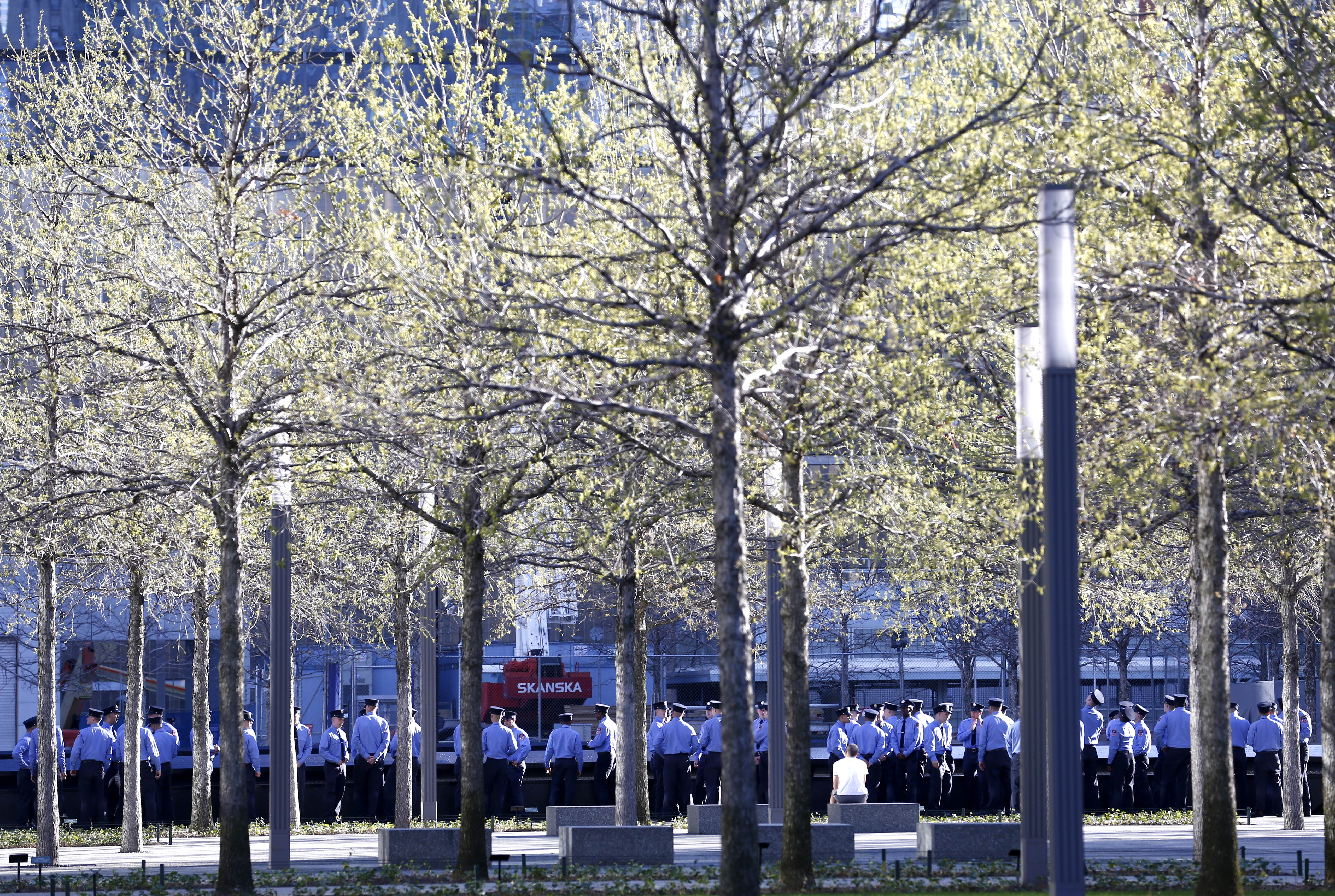 More than 200 probationary FDNY firefighters visit 9/11 Memorial plaza. They are seen gathered around a reflecting pool underneath the Memorial’s swamp white oaks.