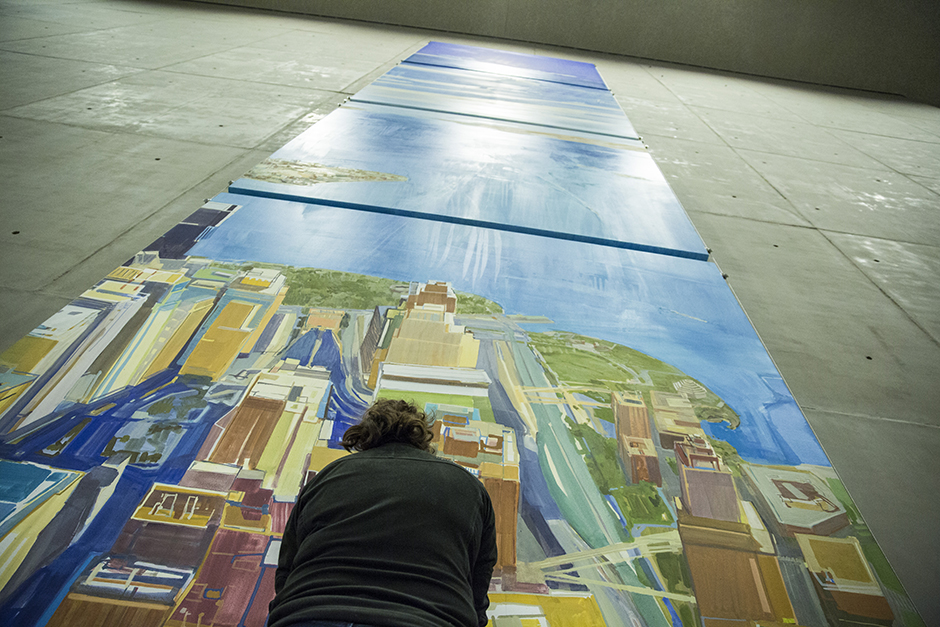 A Museum visitor views the art piece “Looking South” by Daniel Kohn. The artwork, which depicts lower Manhattan and New York Harbor from above, is four-stories tall and towers over the visitor.