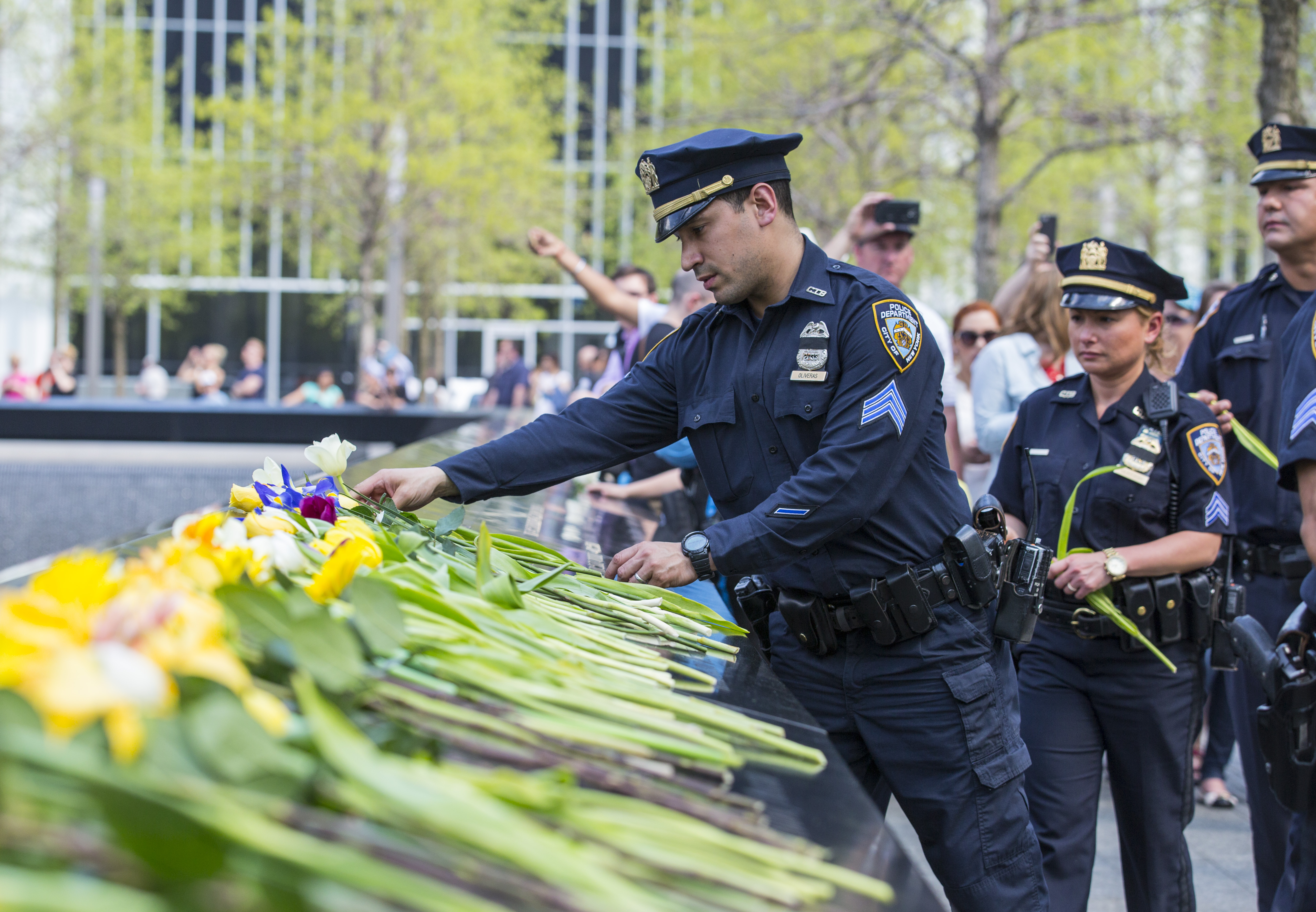 NYPD officers place flowers on the inscribed names of officers who died on 9/11.