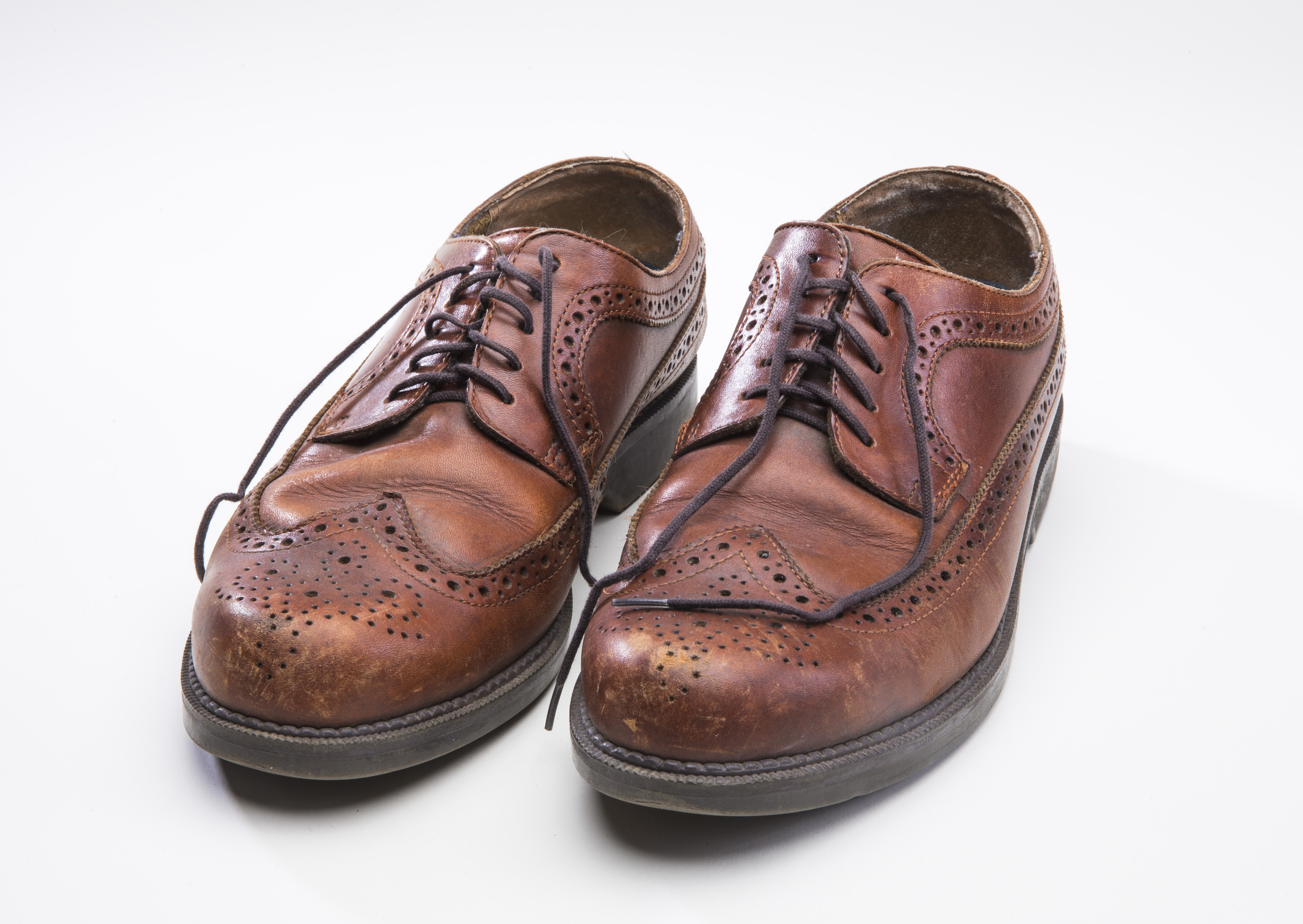 A pair of brown leather dress shoes owned by a 9/11 survivor are displayed on a white surface in the Museum.