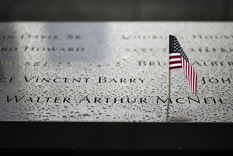 A small American flag has been placed at the name of police officer Walter McNeil. The bronze parapet inscribed with McNeil’s name is covered in drops of rainwater.