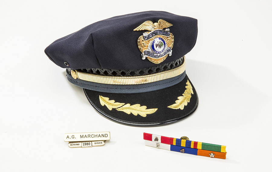 A lieutenant cap and service pins worn by Alfred Gilles Padre Joseph Marchand are displayed on a white surface at the 9/11 Memorial Museum. 