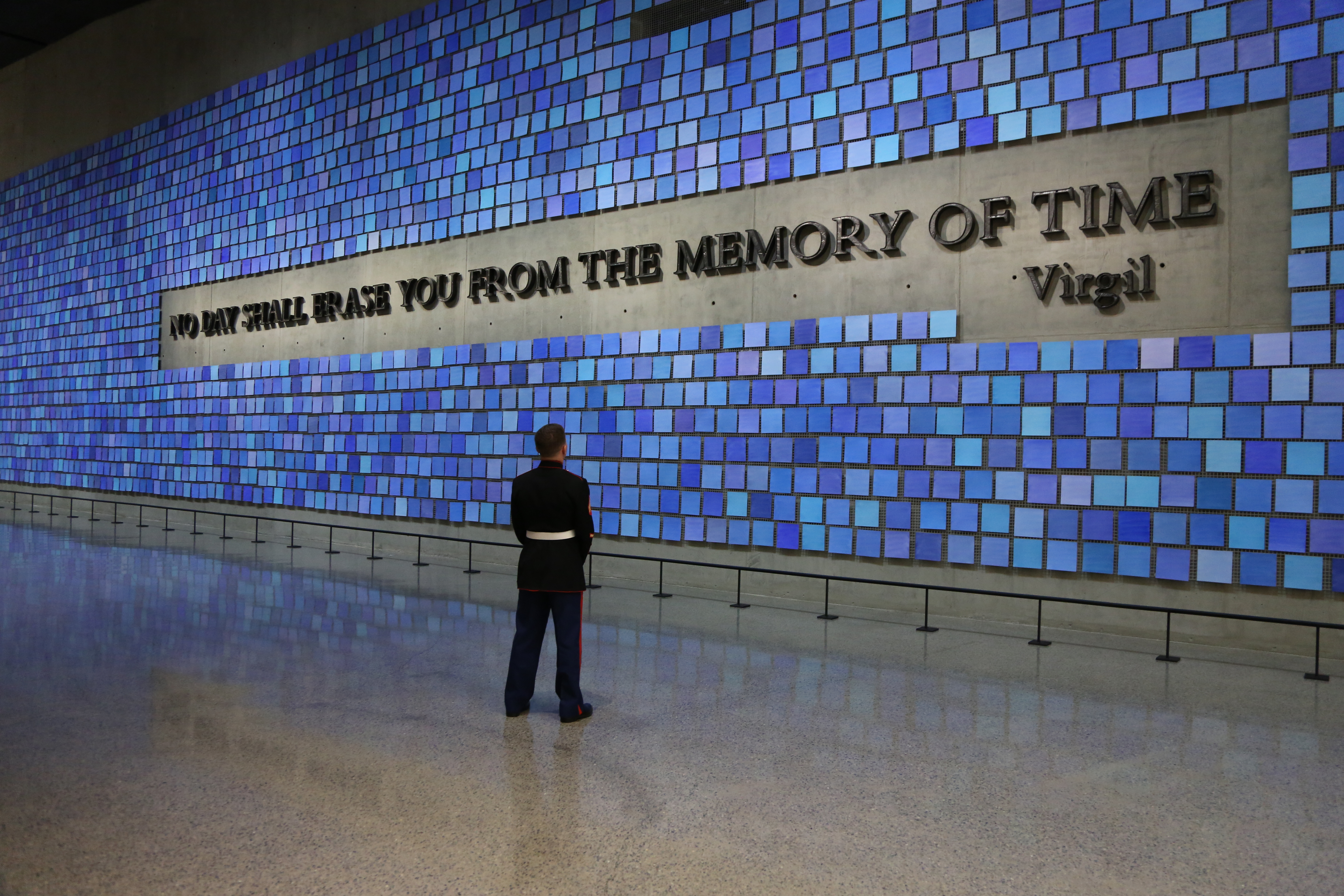 Retired Marine Corporal William Carpenter stands alone in a formal military uniform as he looks at artist Spencer Finch’s Memorial Hall installation “Trying to Remember the Color of the Sky on That September Morning.” The installation includes 2,983 watercolor squares, each in its own shade of blue, and the Virgil quote, “No day shall erase you from the memory of time.”