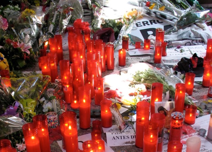 A memorial to victims of the Madrid terrorist attack includes dozens of red candles, flowers, and messages of remembrance.