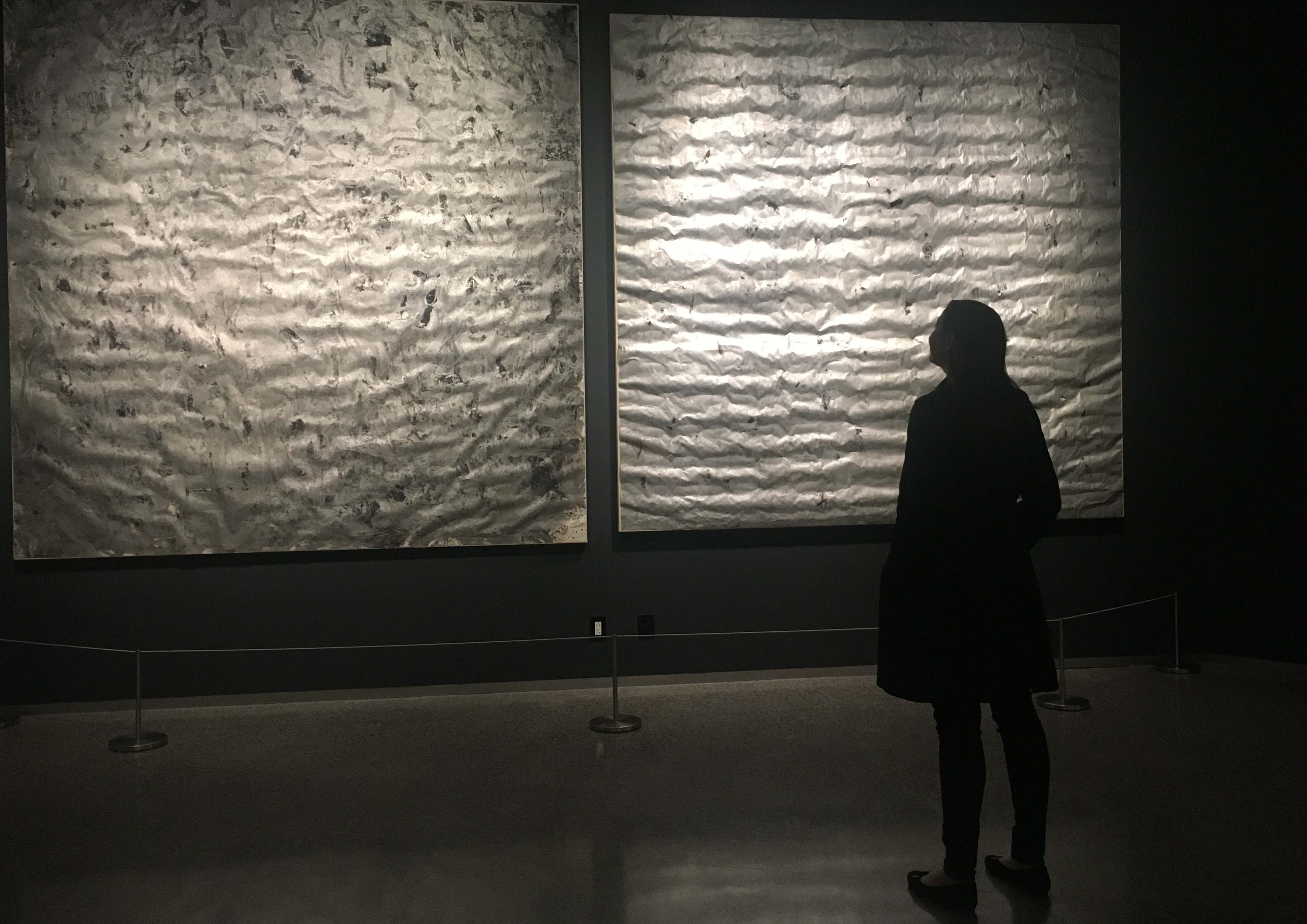 A woman observes artist Michael Mulhern’s series of paintings titled “Ash Road.” The off-gray paintings were created with paint contaminated by the dust from the collapse of the Twin Towers.