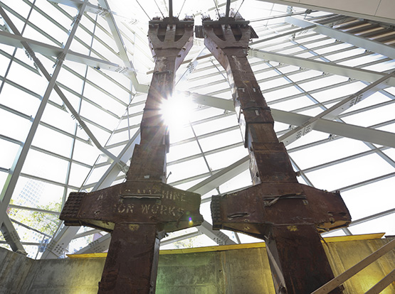 The iconic tridents from the Twin Towers stand at the entrance to the Museum pavilion. Sunlight shines through the windows between the towers as they rise towards the ceiling.