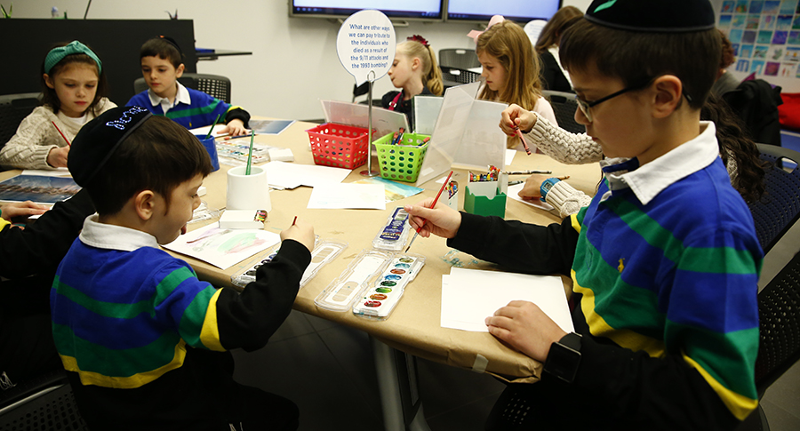 Children take part in an art activity at the Museum’s Education Center. In the foreground, two boys paint on pieces of paper.