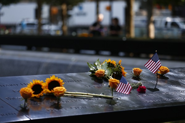 Yellow roses, sunflowers and two, small American flags are seen on a bronze parapet at the 9/11 Memorial.