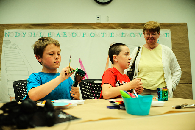 A woman watches on as two boys work on an art project in the Museum’s Education Center.