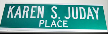 A green and white street sign reads Karen S. Juday Place.