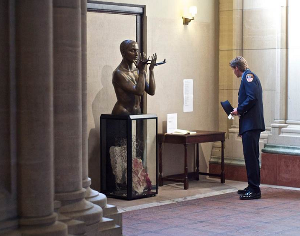 A firefighter in a formal FDNY outfit looks at a sculpture by Meredith Bergmann at the Cathedral of St. John the Divine on the Upper West Side.