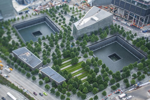 An aerial view of the Memorial shows the twin reflecting pools, the Museum pavilion, and the many trees that line the plaza.