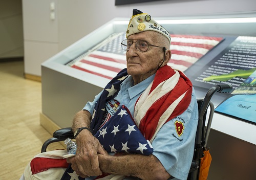 John Seelie, a U.S. Army veteran and Pearl Harbor survivor, holds an American flag as he sits in a wheelchair during a visit to the 9/11 Memorial Museum.