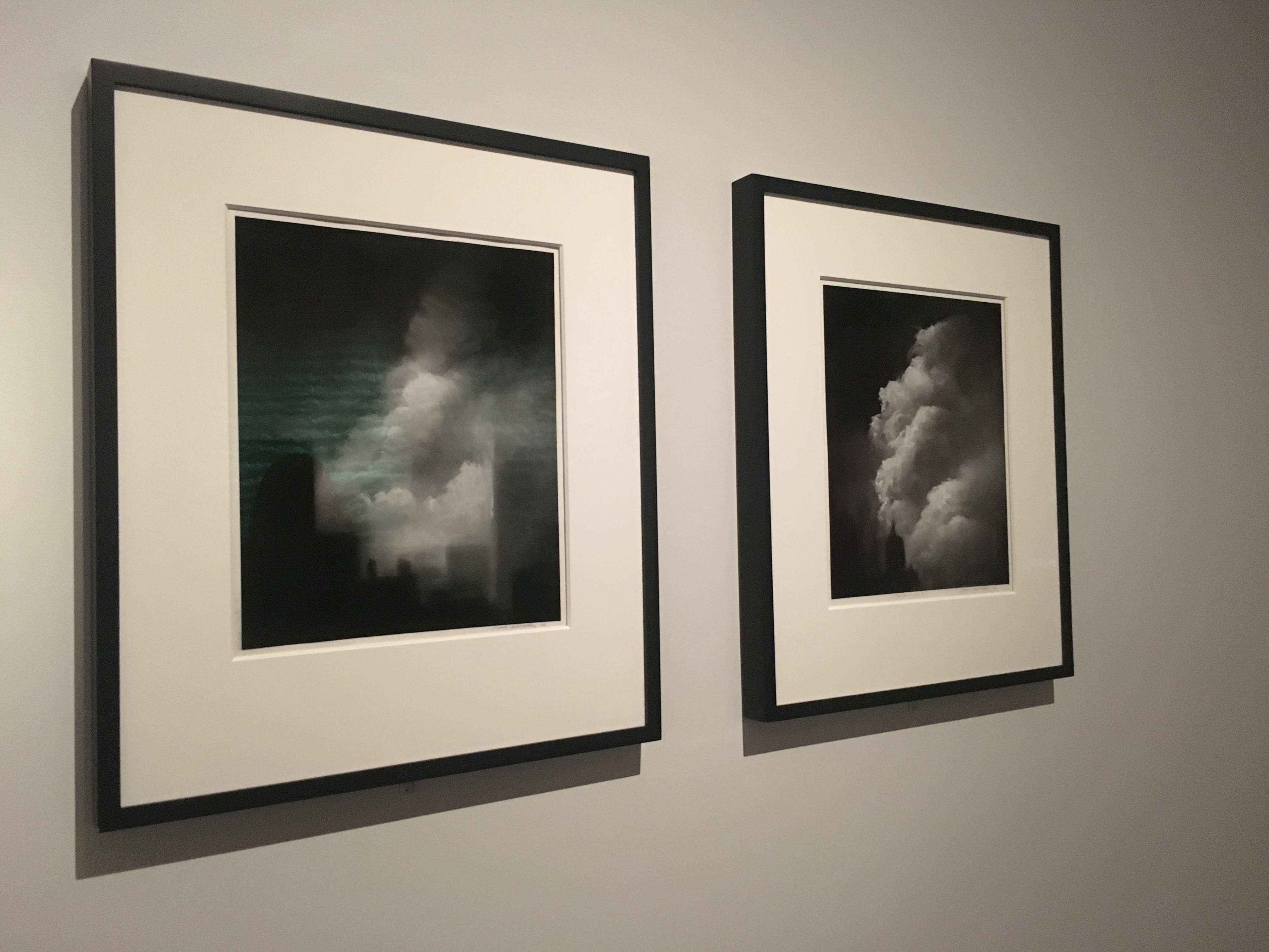 Two framed pieces of art by artist Donna Levinstone are displayed on a white wall. The handmade pastels show plumes of smoke and dust in lower Manhattan.