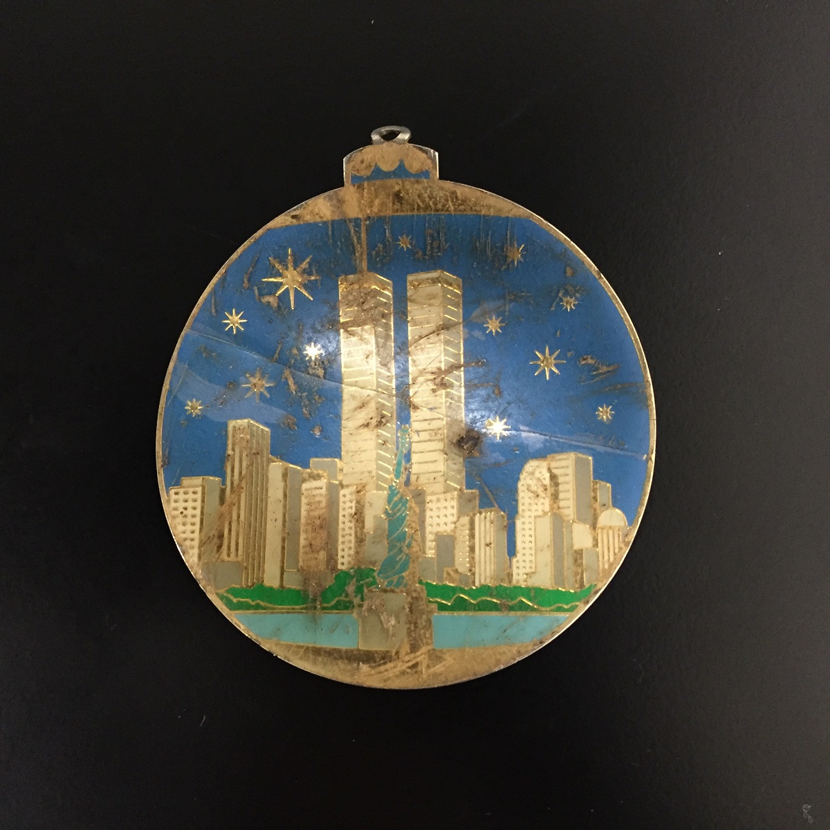 An ornament recovered at Ground Zero is displayed on a black surface. The ornament depicts the Twin Towers on a starry night.