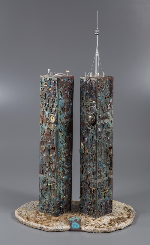 A copper sculpture by artist Michael Cooper depicts the Twin Towers covered in a miscellany of peace-related, religious, and pagan symbology.
