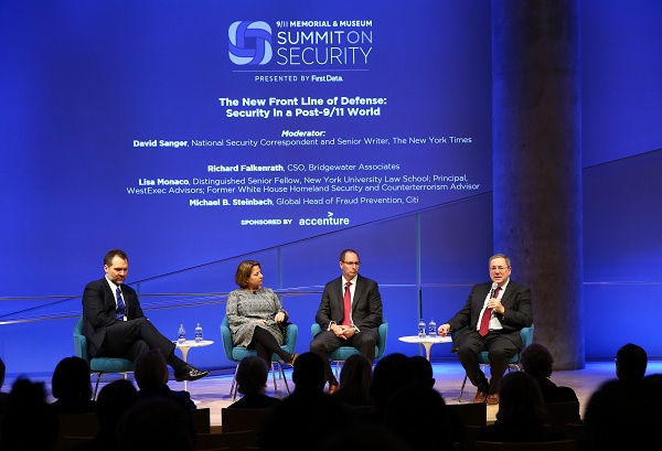 Three men in suits and a woman in a dress sit onstage at the Museum auditorium as they take part in a panel at the Summit on Security.