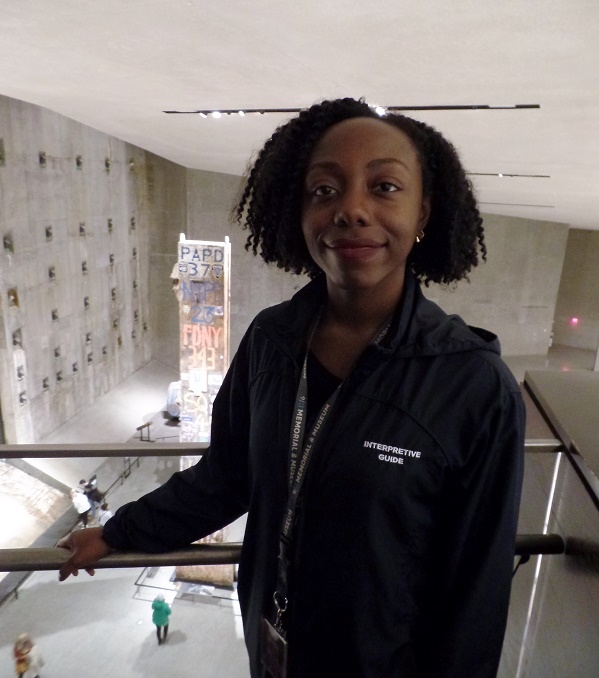 Nyantee Asherman, a senior interpretive guide at the 9/11 Memorial Museum, stands on the walkway leading to Foundation Hall. The Last Column can be seen in the background.
