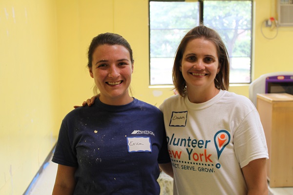 Two female volunteers embrace for a photo while painting a yellow-colored room at a Head Start learning center in Mount Vernon, New York.