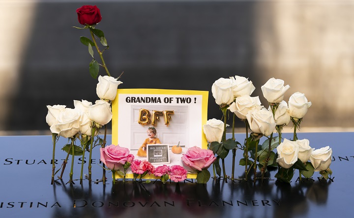 A tribute card is left on the Memorial parapet and is ringed by fresh white and pink roses.