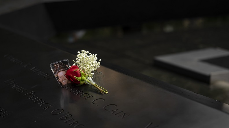 A flower bouquet and a laminated photo of an FDNY firefighter are left on the memorial parapet for the 19th anniversary.