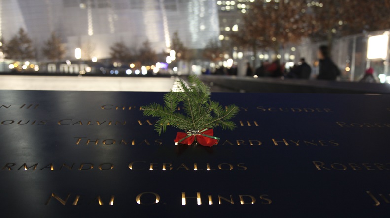 A red flower and pine needle bouquet left on the 9/11 Memorial parapet at night.