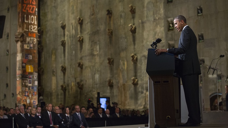 President Barack Obama speaks in Foundation Hall at the dedication of the 9/11 Memorial Museum on May 15, 2014. Former President Bill Clinton, Secretary of State Hillary Clinton, former New York Governor George Pataki, former Mayor Rudy Giuliani, and others watch on with the Last Column and slurry wall behind them.