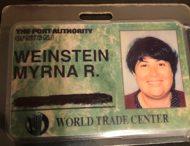 Battered Port Authority/World Trade Center identification card with photo of smiling woman with short, dark hair on right and her name - WEINSTEIN, MYRNA R. - on the right.