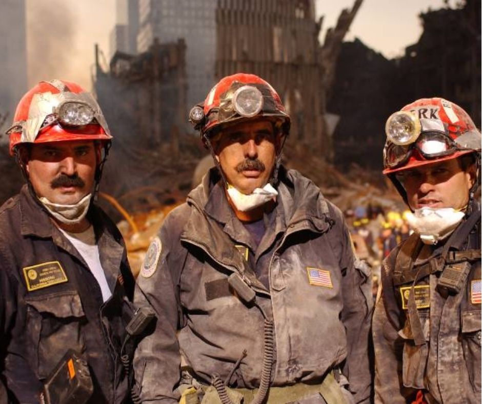 A trio of Ground Zero rescue and recovery workers wearing red hard hats and khaki uniforms