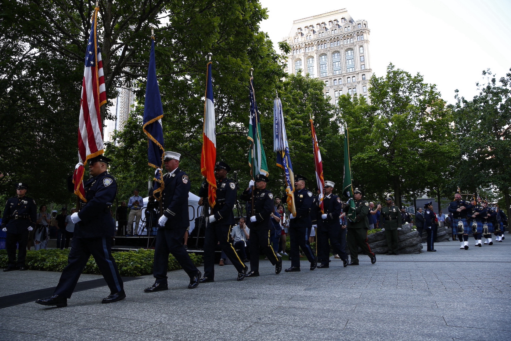 Uniformed officers carry flags in a procession on the plaza